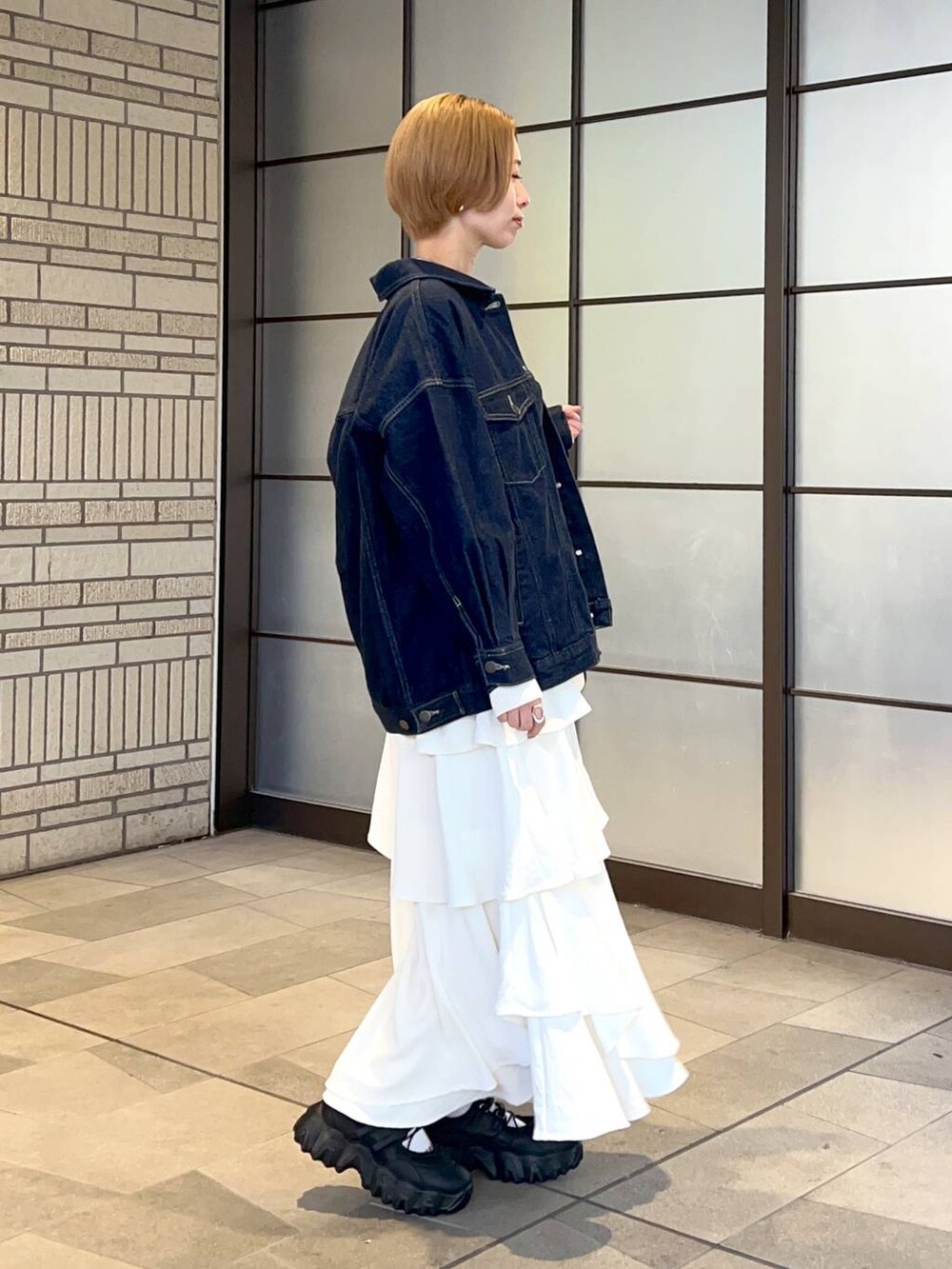 ブラック系のトートバッグ、ホワイト系のスカート、ブルー系のデニムジャケットを着用したレディースの冬コーディネートの2枚目の写真