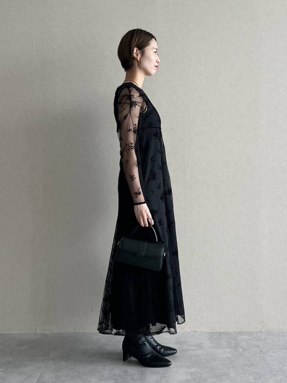 ブラック系のワンピース、パープル系のチェスターコート、ブラック系のブーツを着用したレディースの秋コーディネートの5枚目の写真