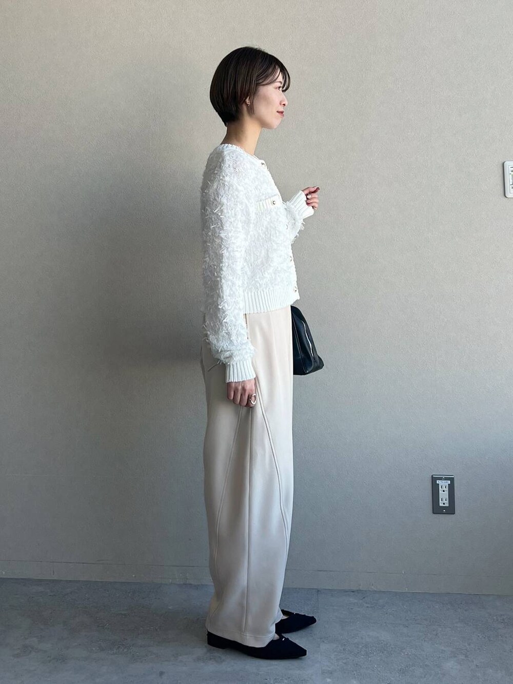 ブラック系のトートバッグ、ホワイト系のカーディガン/ボレロ、ブラック系のパンプスを着用したレディースの冬コーディネートの5枚目の写真