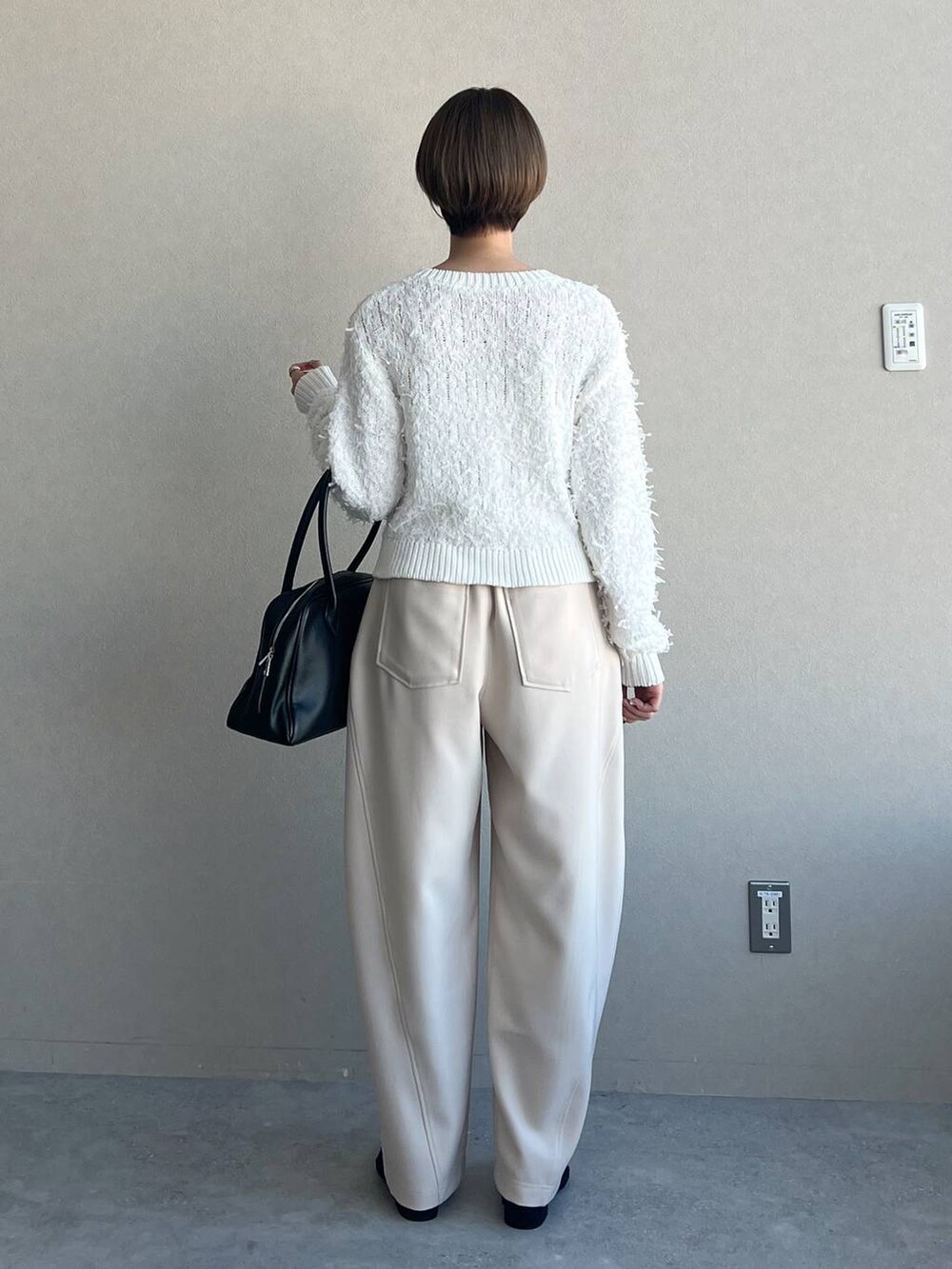 ブラック系のトートバッグ、ホワイト系のカーディガン/ボレロ、ブラック系のパンプスを着用したレディースの冬コーディネートの6枚目の写真