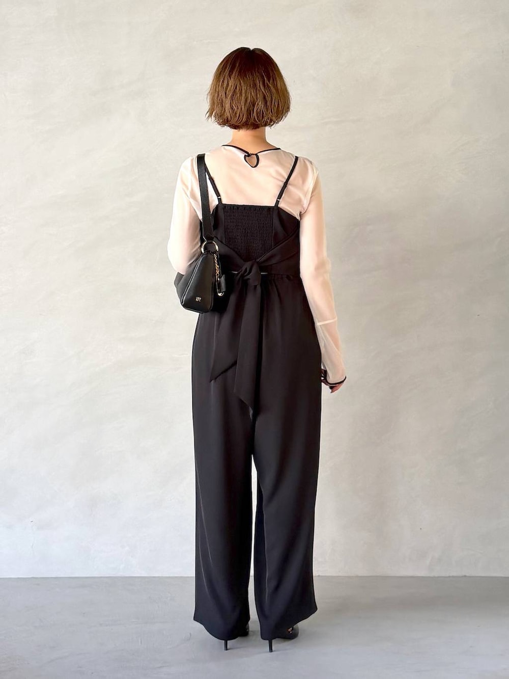 ブラック系のサンダル、ブラック系のショルダーバッグ、ブラック系のパンツドレスを着用したレディースの春コーディネートの3枚目の写真