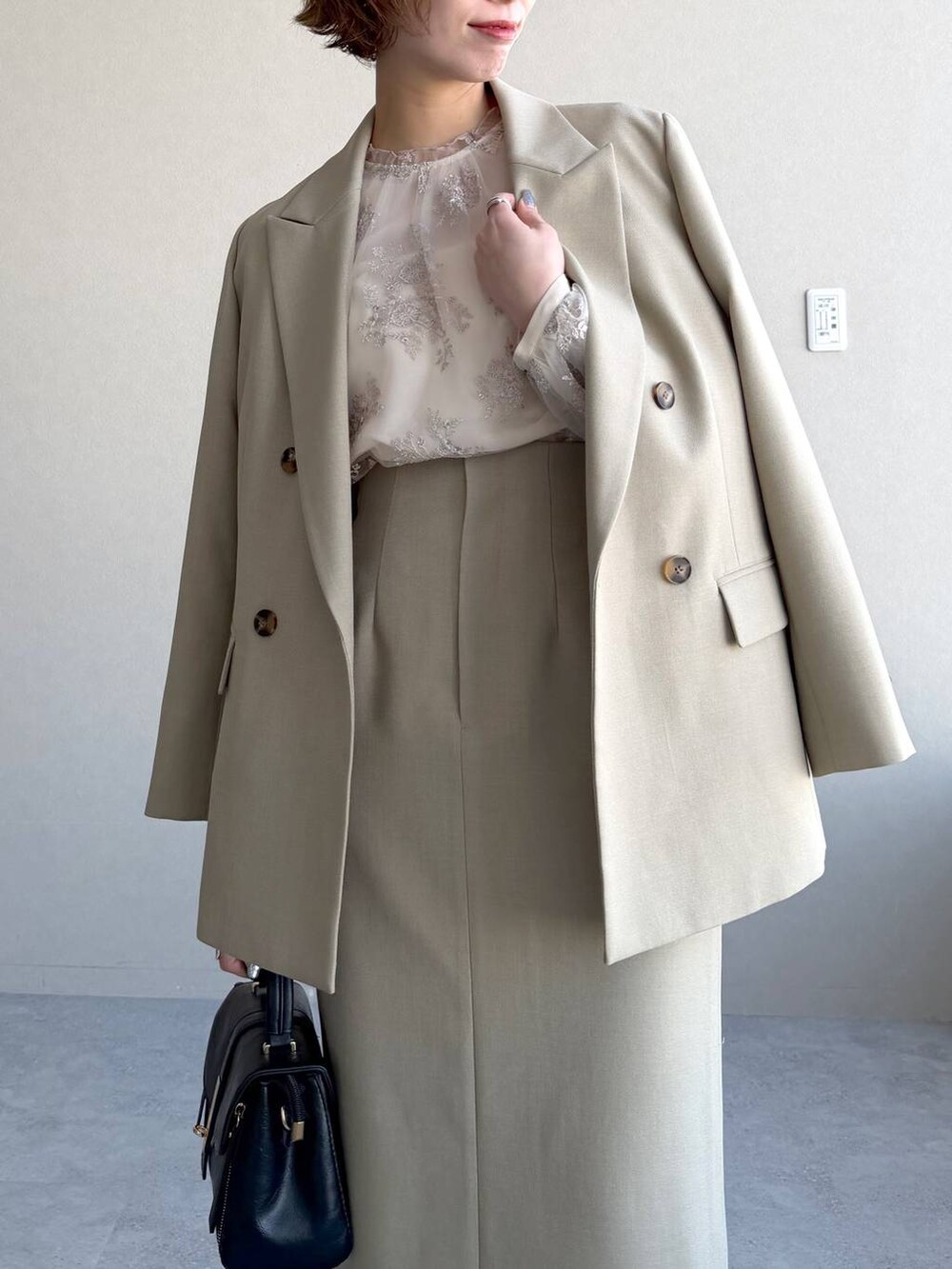 ブラック系のショルダーバッグ、ベージュ系のテーラードジャケット、ベージュ系のスカートを着用したレディースの冬コーディネートの7枚目の写真