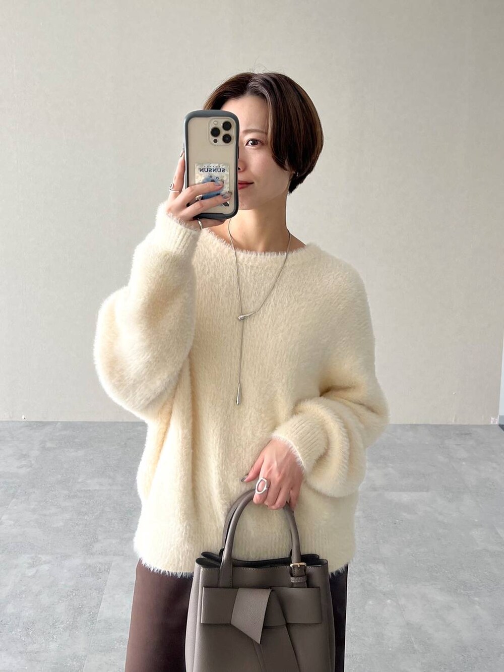 ベージュ系のショルダーバッグ、ブラウン系のスカート、ブラック系のブーツを着用したレディースの秋コーディネートの5枚目の写真