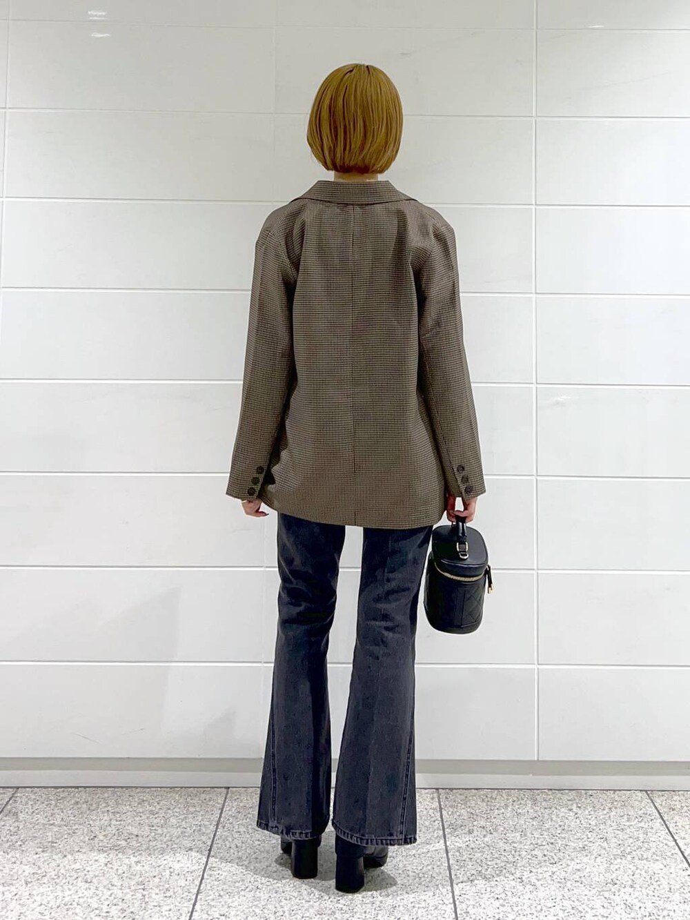 ブラック系のデニムパンツ、ブラック系のブーツ、ブラック系のショルダーバッグを着用したレディースの秋コーディネートの3枚目の写真