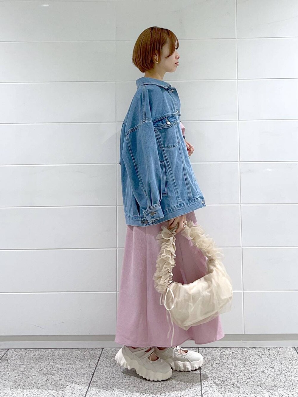 ベージュ系のショルダーバッグ、ブルー系のデニムジャケット、ホワイト系のバレエシューズを着用したレディースの春コーディネートの2枚目の写真