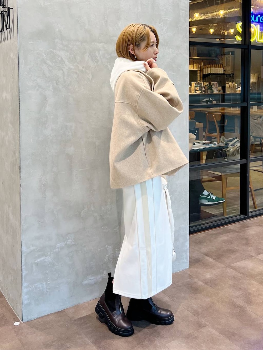 ベージュ系のピーコート、ホワイト系のショルダーバッグ、ブラウン系のブーツを着用したレディースの秋コーディネートの2枚目の写真