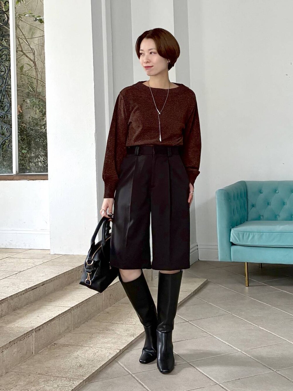 ブラウン系のニット/セーター、ブラック系のボストンバッグ、ブラック系のブーツを着用したレディースの冬コーディネートの4枚目の写真