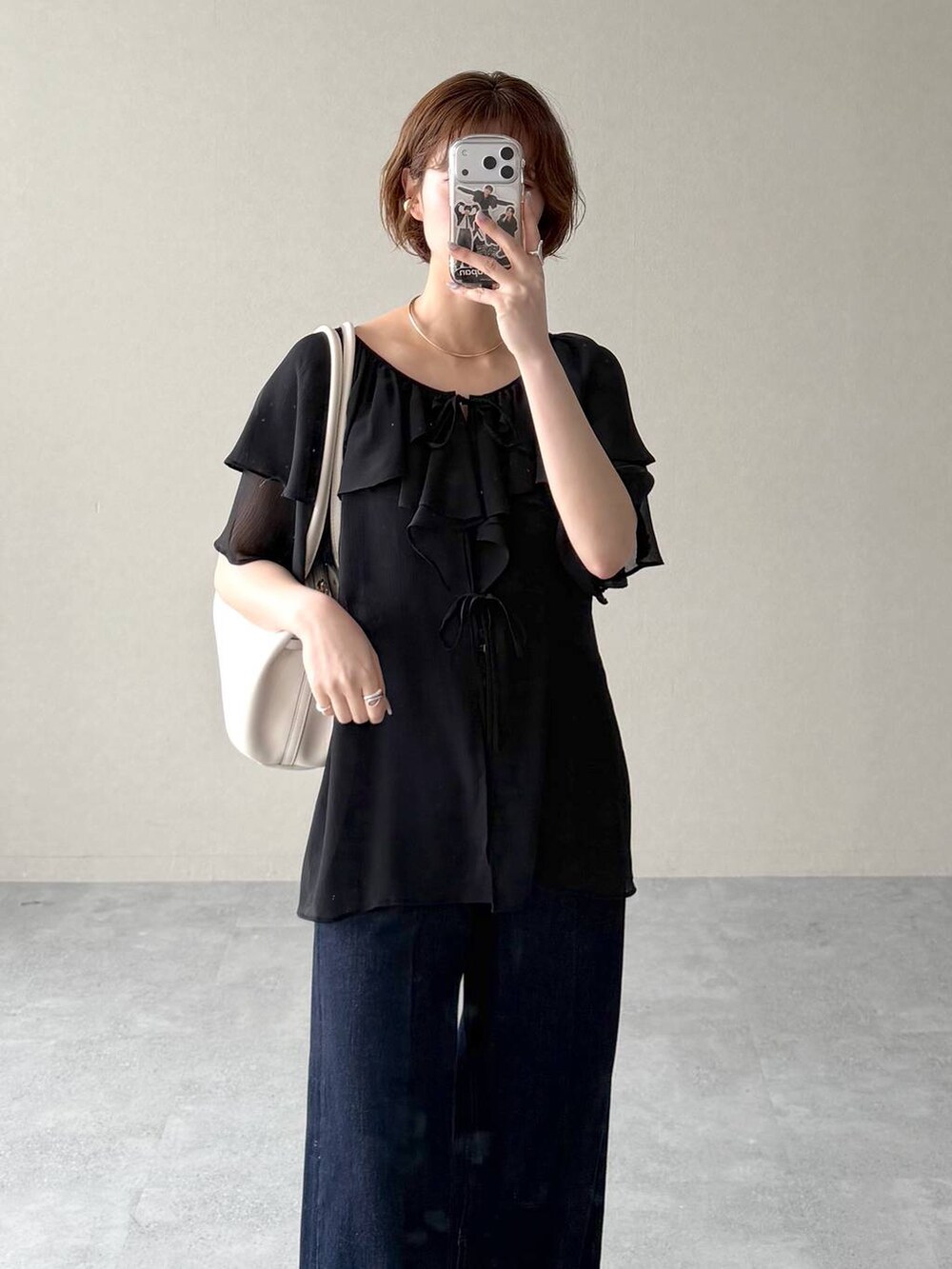 ホワイト系のサンダル、ブルー系のデニムパンツ、ブラック系のシャツ/ブラウスを着用したレディースの春コーディネートの5枚目の写真