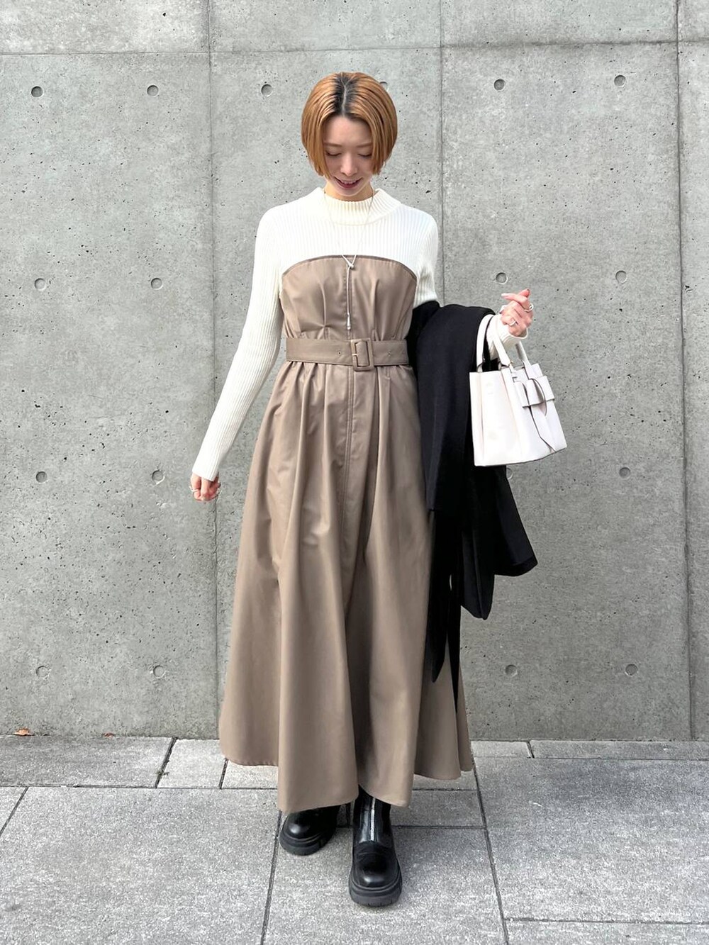 ブラック系のノーカラーコート、ブラック系のブーツ、ホワイト系のショルダーバッグを着用したレディースの冬コーディネートの4枚目の写真