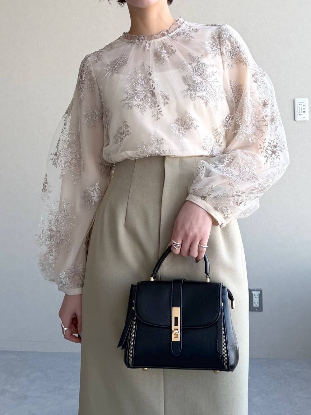 ブラック系のショルダーバッグ、ベージュ系のテーラードジャケット、ベージュ系のスカートを着用したレディースの冬コーディネートの8枚目の写真