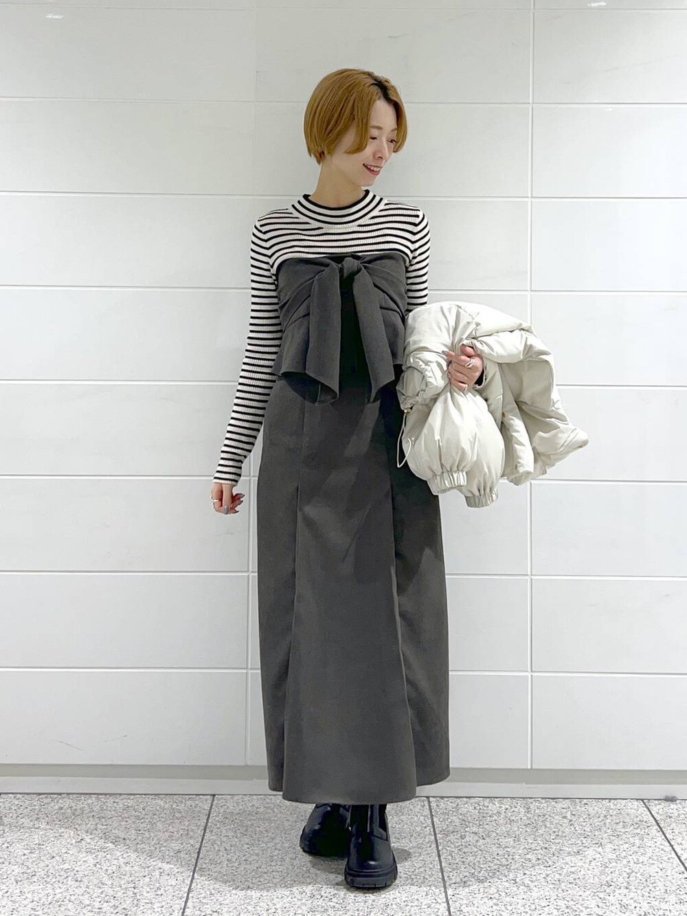 ブラック系のブーツ、ブラック系のニット/セーター、ホワイト系のブルゾンを着用したレディースの冬コーディネートの4枚目の写真