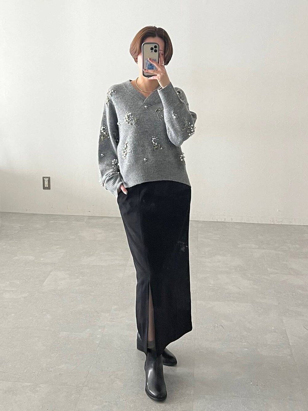 グレー系のニット/セーター、ブラック系のスカート、ブラック系のブーツを着用したレディースの秋コーディネートの5枚目の写真