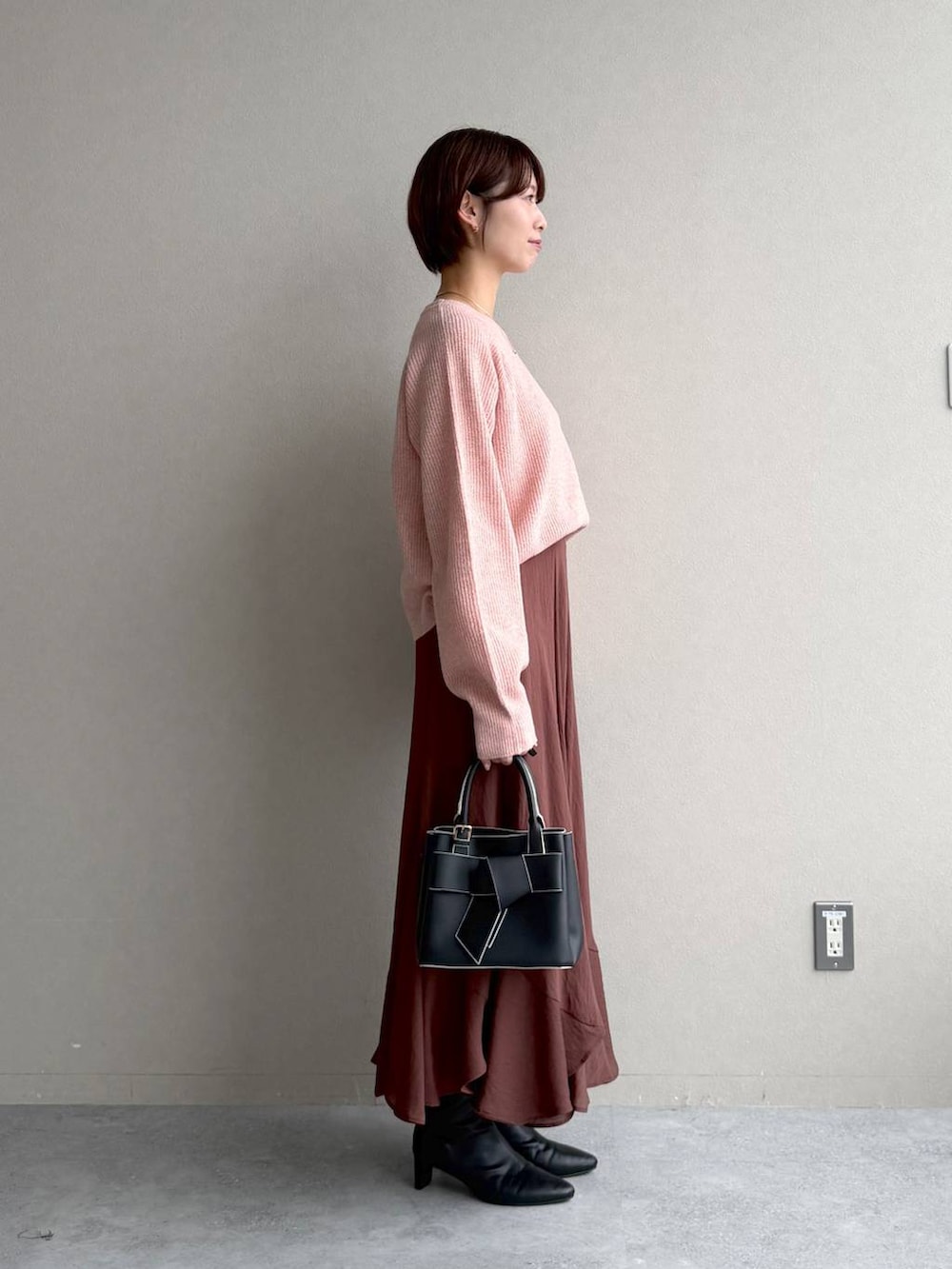 ピンク系のニット/セーター、ブラック系のショルダーバッグ、ブラウン系のスカートを着用したレディースの秋コーディネートの2枚目の写真