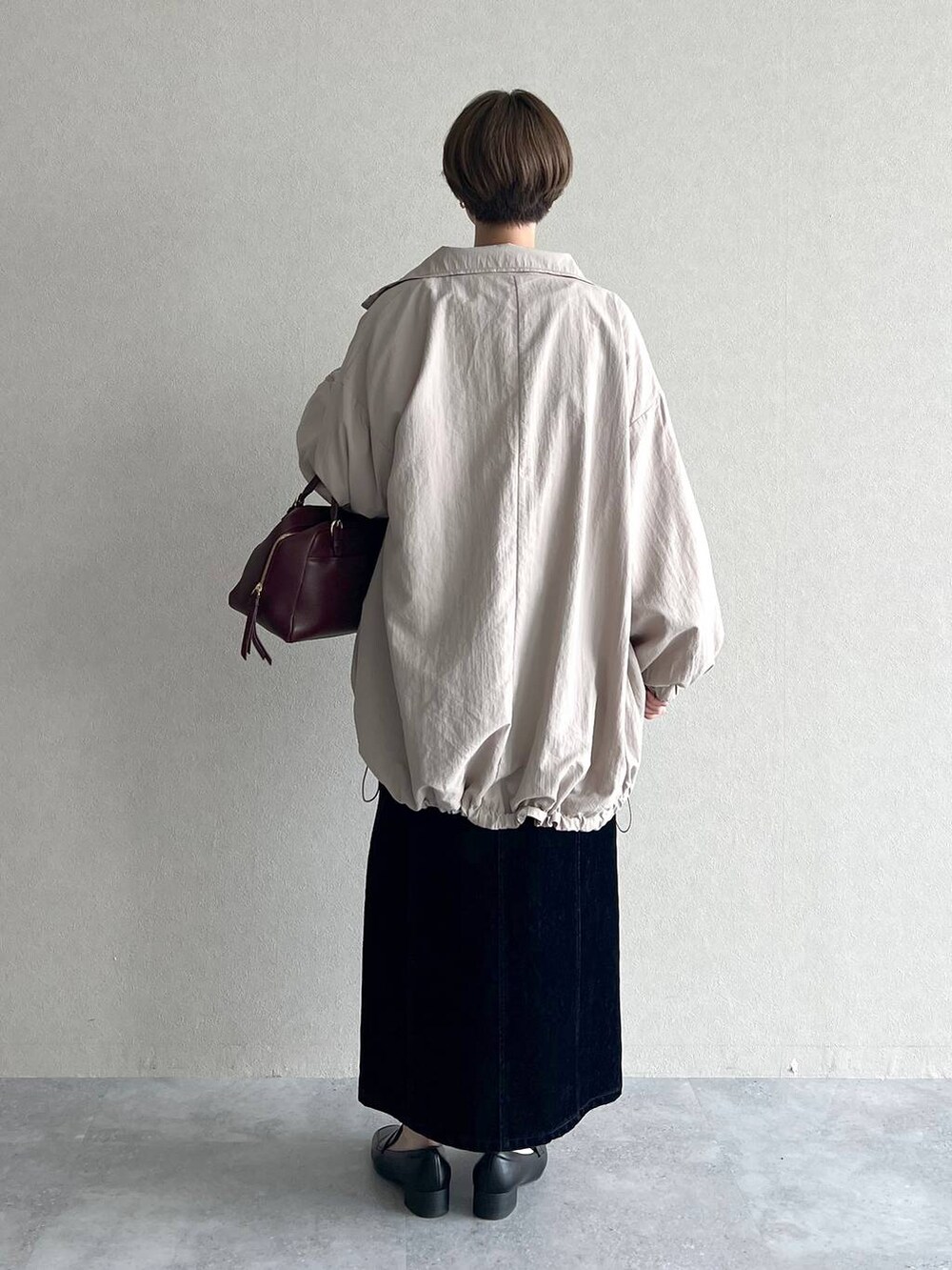 レッド系のハンドバッグ、ブラック系のスカート、ブラック系のローファーを着用したレディースの秋コーディネートの3枚目の写真