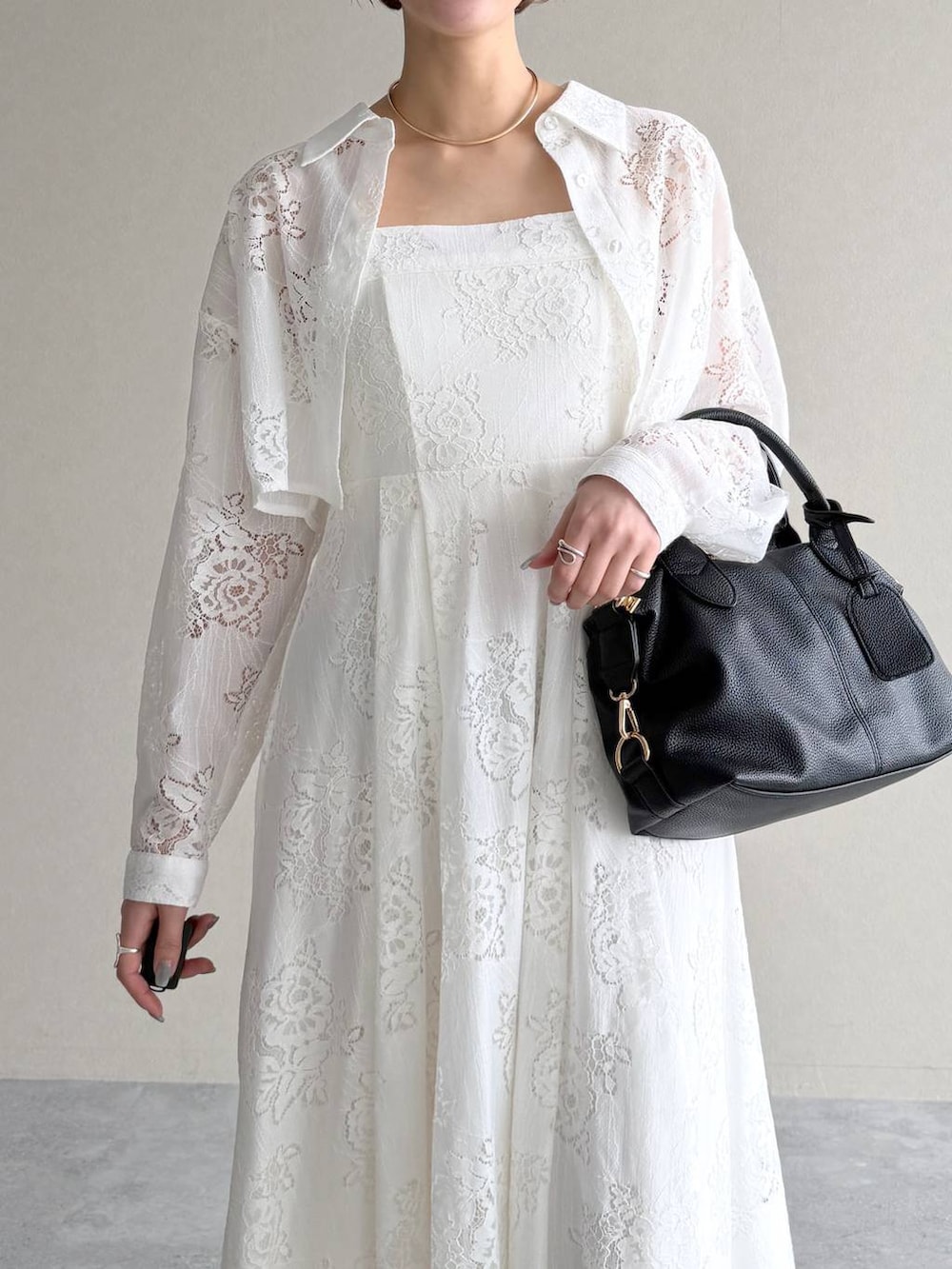 ブラック系のボストンバッグ、ブラック系のサンダル、ホワイト系のワンピースを着用したレディースの春コーディネートの5枚目の写真