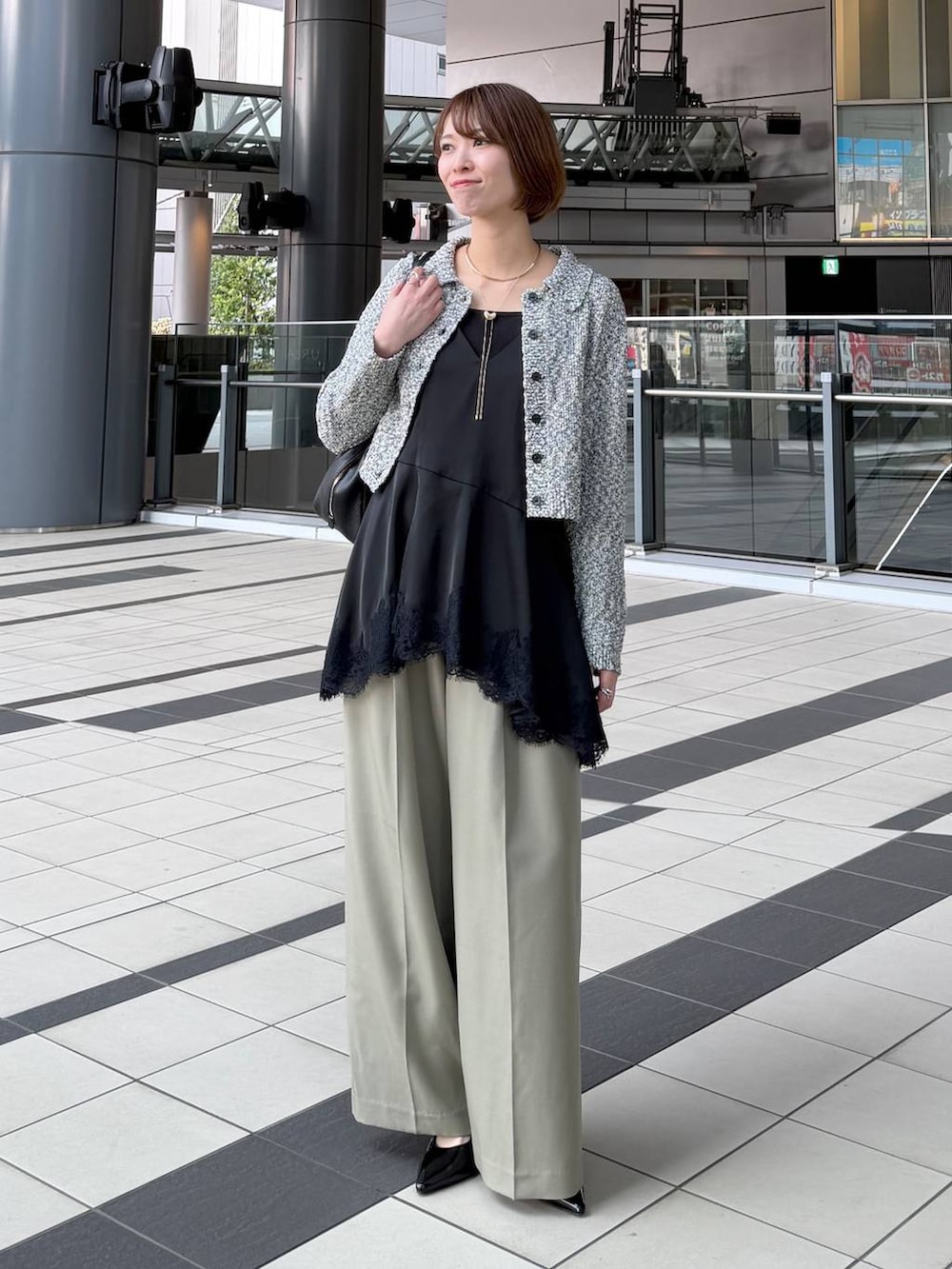 ブラック系のハンドバッグ、ブラック系のサンダル、ブラック系のキャミソールを着用したレディースの春コーディネートの6枚目の写真