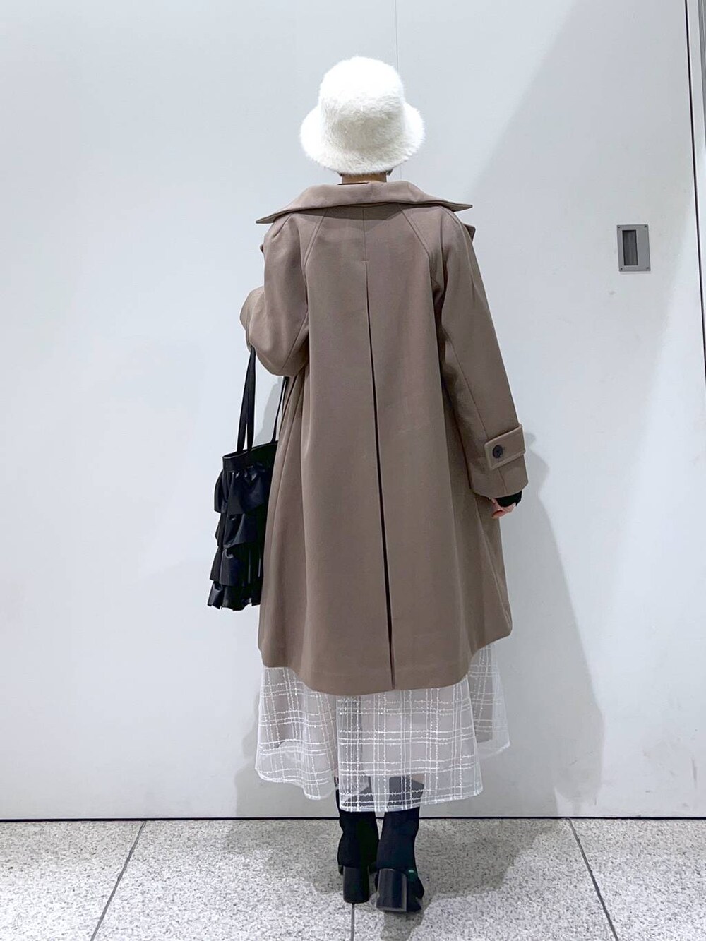 ブラウン系のチェスターコート、ブラック系のブーツ、ブラック系のニット/セーターを着用したレディースの冬コーディネートの3枚目の写真