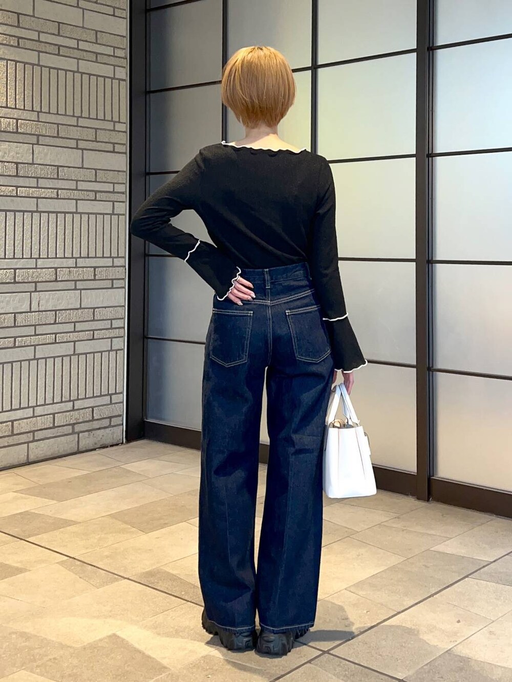 ホワイト系のブルゾン、ホワイト系のショルダーバッグ、ブルー系のスラックスを着用したレディースの冬コーディネートの6枚目の写真