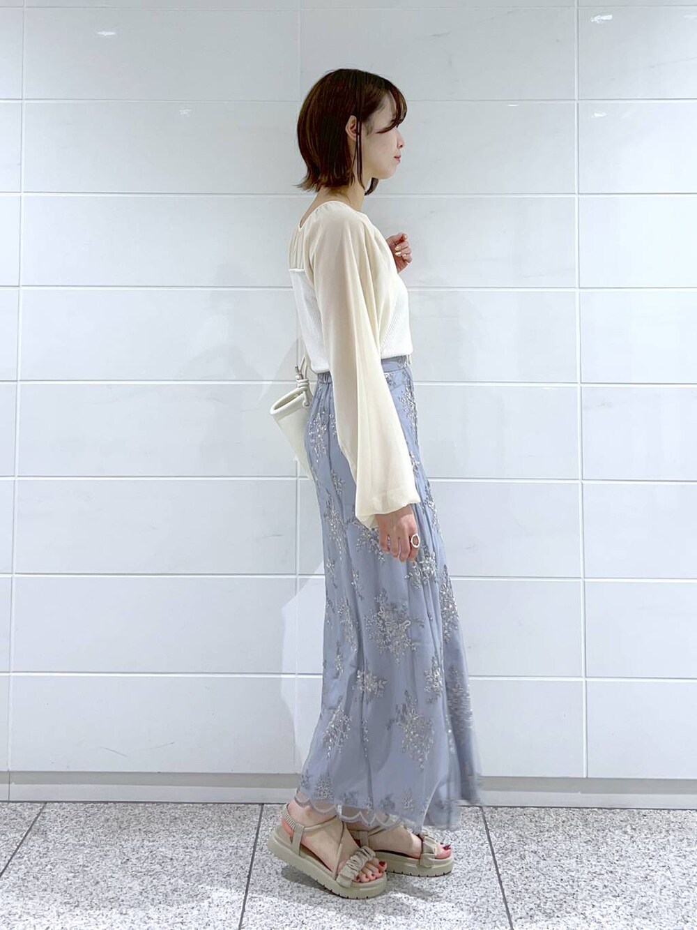 ブルー系のスカート、ホワイト系のTシャツ/カットソー、ホワイト系のサンダルを着用したレディースの春コーディネートの2枚目の写真