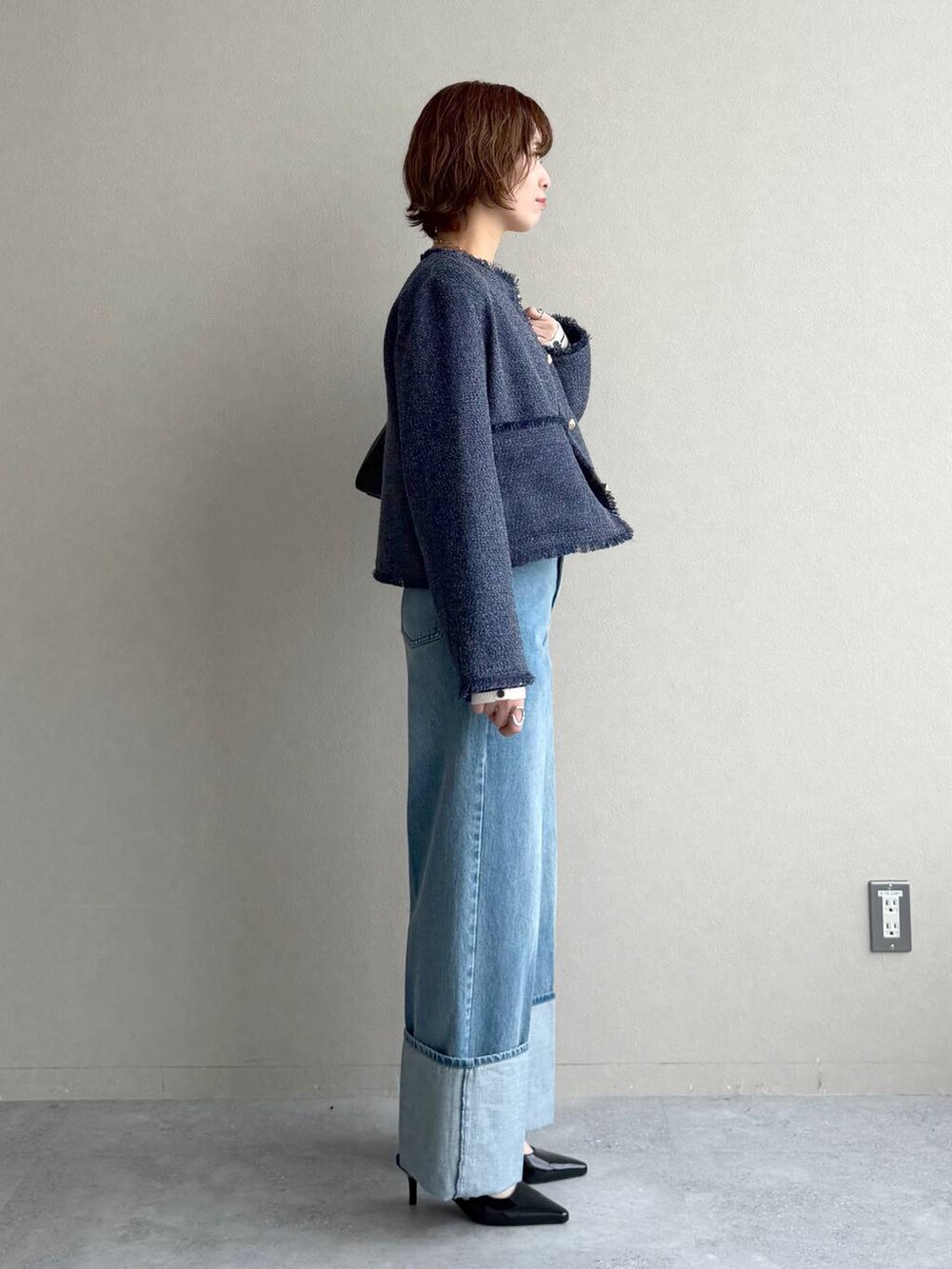 グレー系のニット/セーター、ブラック系のサンダル、ブルー系のノーカラージャケットを着用したレディースの冬コーディネートの2枚目の写真