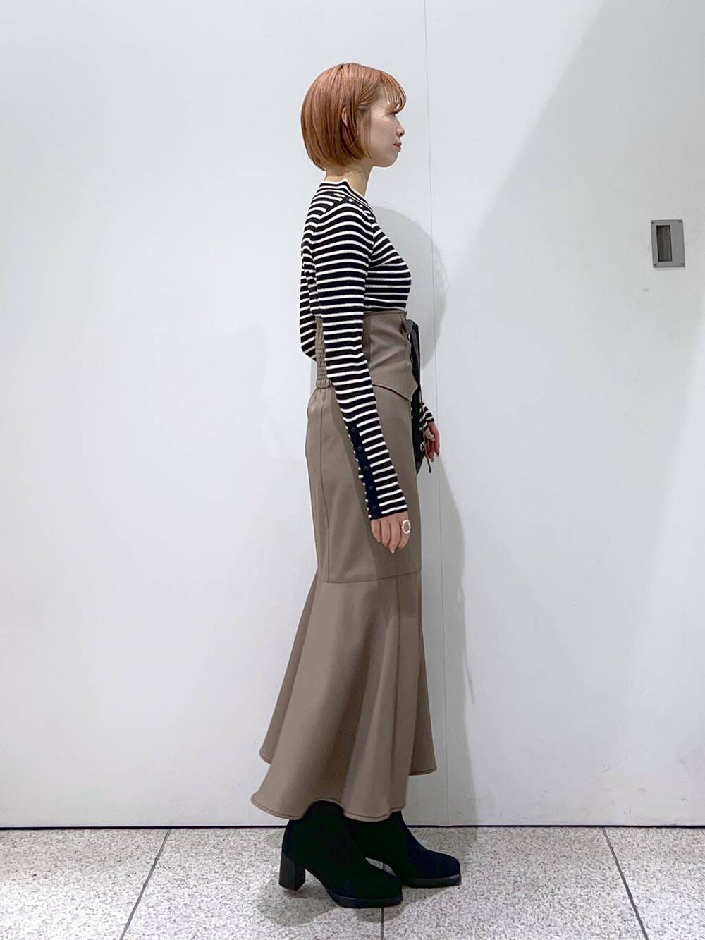 ブラック系のショルダーバッグ、ブラック系のブーツ、ブラウン系のスカートを着用したレディースの冬コーディネートの5枚目の写真