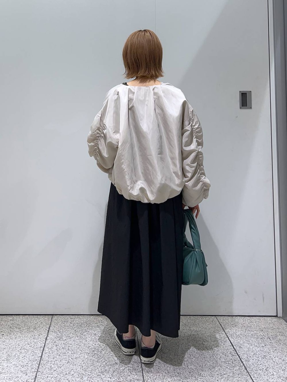 ブラック系のTシャツ/カットソー、ホワイト系のブルゾン、グリーン系のハンドバッグを着用したレディースの秋コーディネートの2枚目の写真