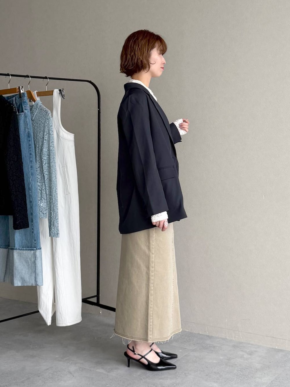 ブラック系のサンダル、ブルー系のテーラードジャケット、ベージュ系のスカートを着用したレディースの春コーディネートの2枚目の写真