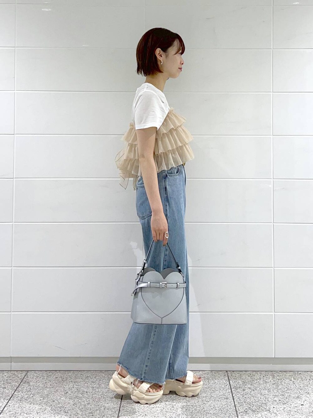 ブルー系のデニムパンツ、ホワイト系のサンダル、シルバー系のショルダーバッグを着用したレディースの夏コーディネートの2枚目の写真