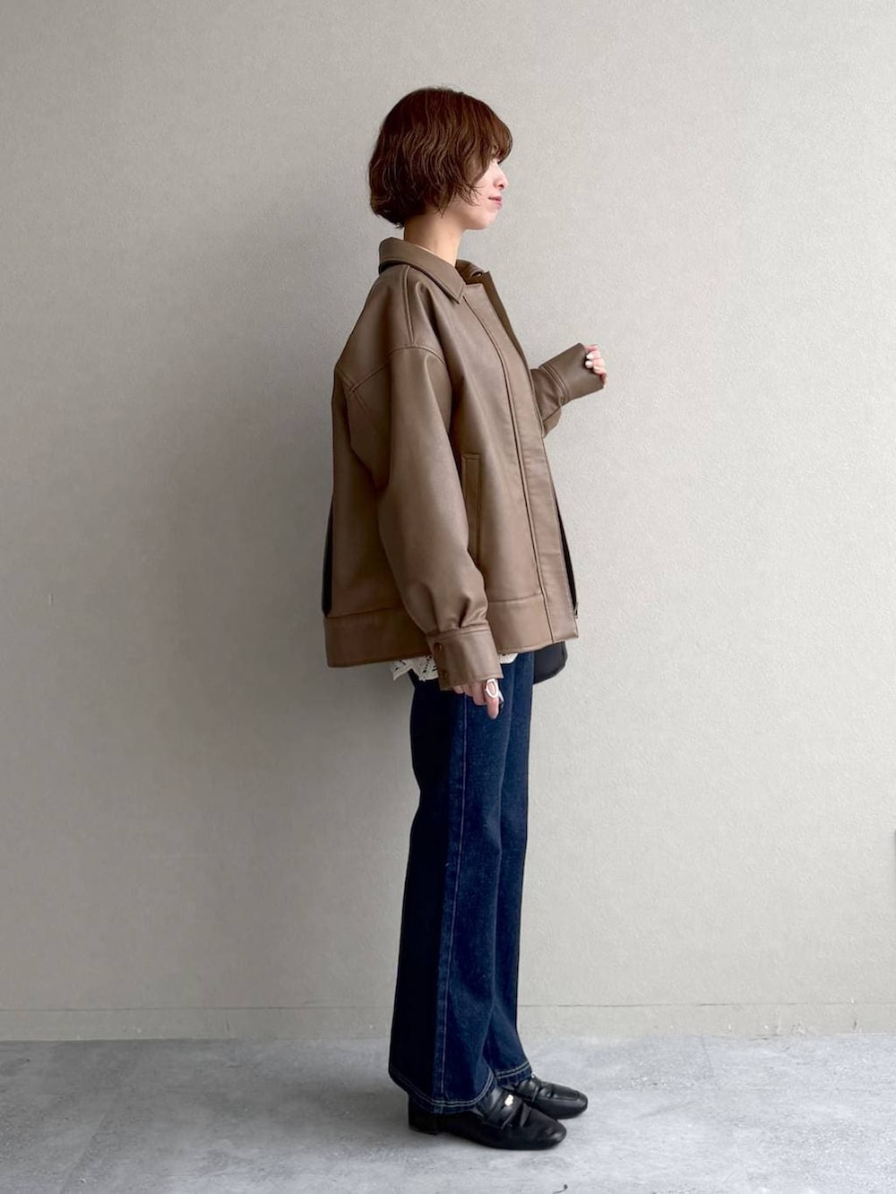 ブラック系のローファー、ブルー系のデニムパンツ、ブラウン系のブルゾンを着用したレディースの春コーディネートの2枚目の写真