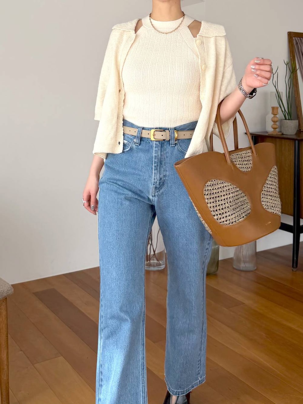 ブラウン系のトートバッグ、ブルー系のデニムパンツ、ブラック系のサンダルを着用したレディースの春コーディネートの5枚目の写真