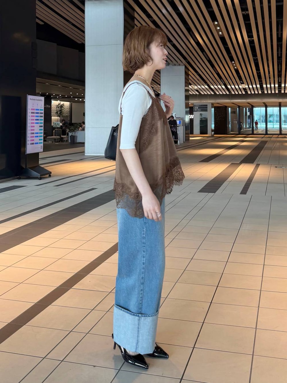 ブラック系のサンダル、ブラウン系のキャミソール、ホワイト系のノーカラージャケットを着用したレディースの春コーディネートの5枚目の写真