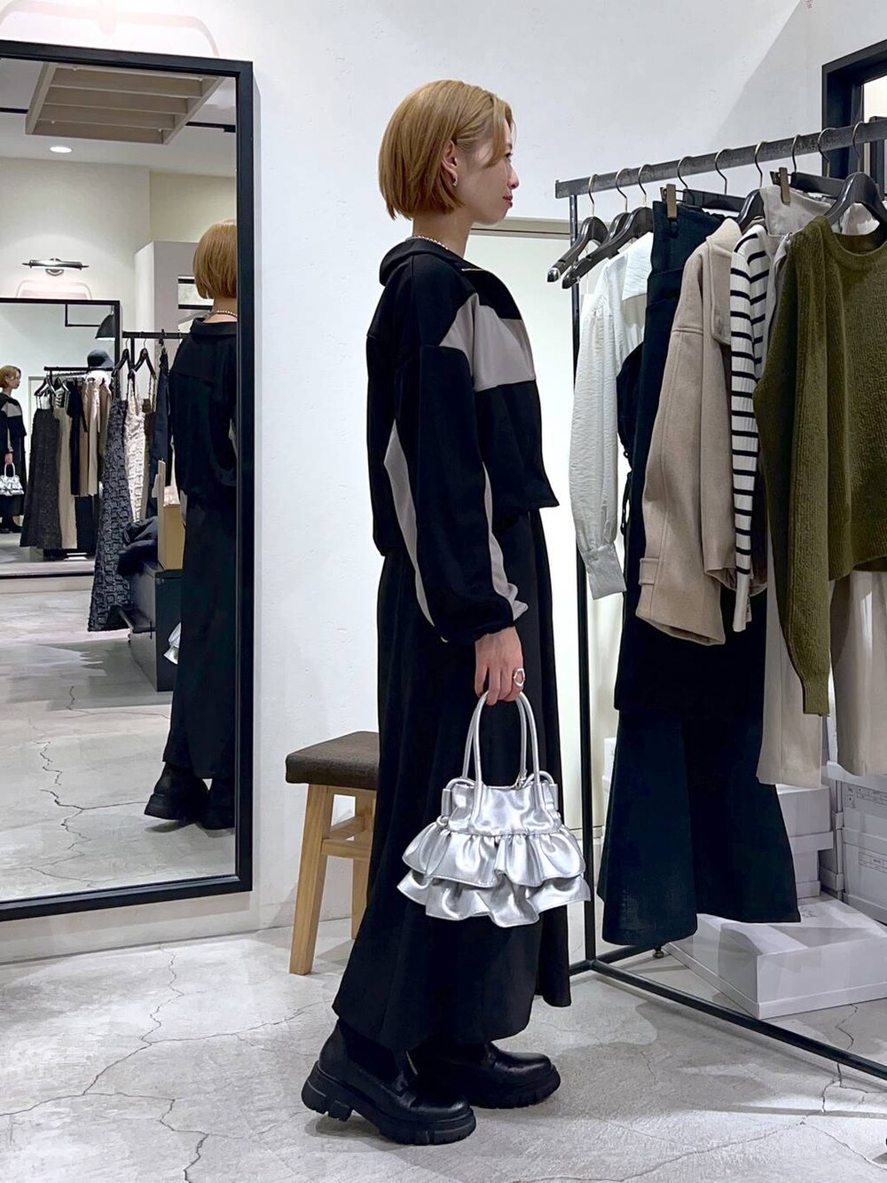 シルバー系のショルダーバッグ、ブラック系のブーツ、ブラック系のワンピースを着用したレディースの秋コーディネートの2枚目の写真