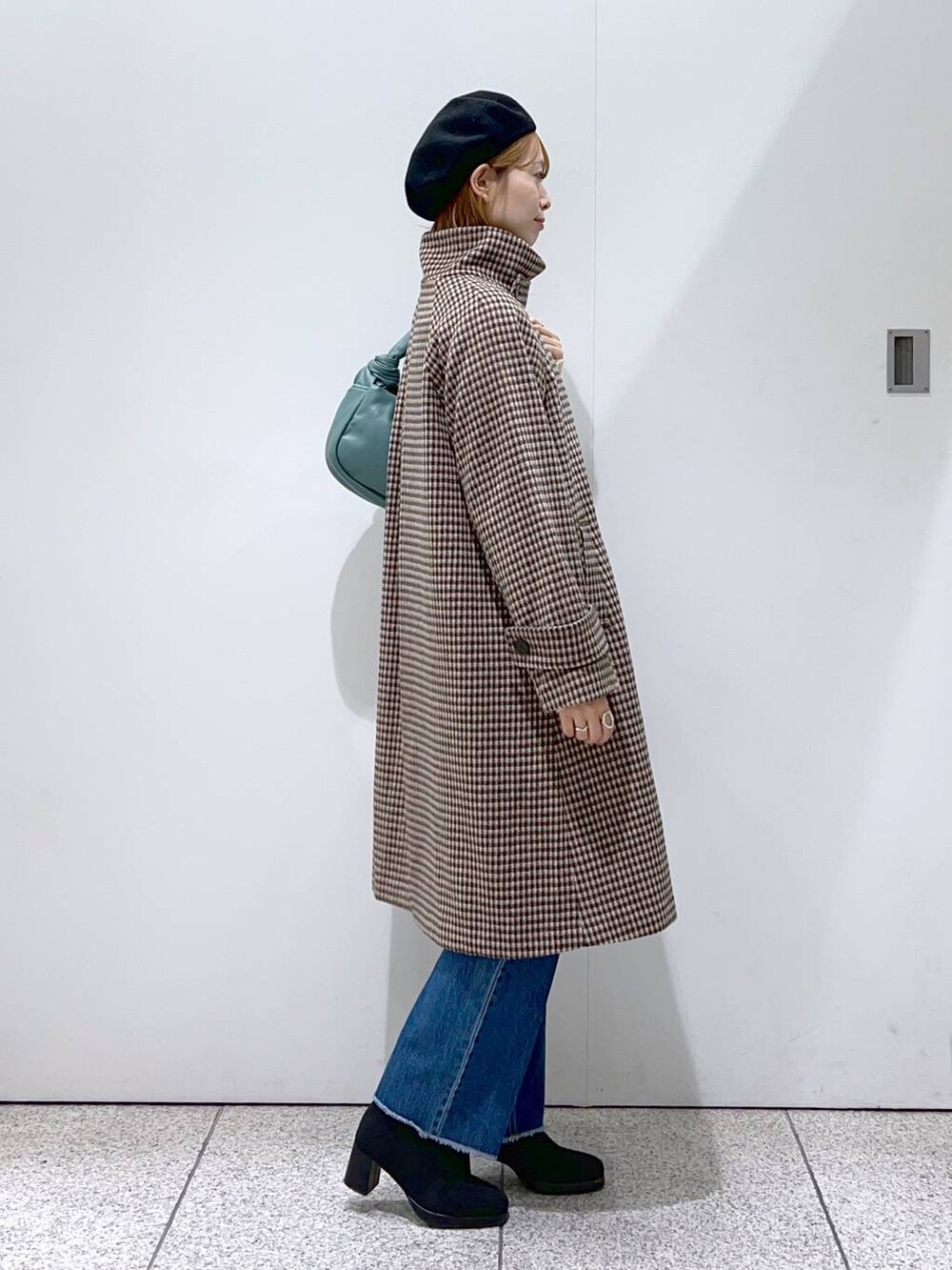 ブルー系のデニムパンツ、ブラック系のブーツ、ホワイト系のニット/セーターを着用したレディースの秋コーディネートの2枚目の写真