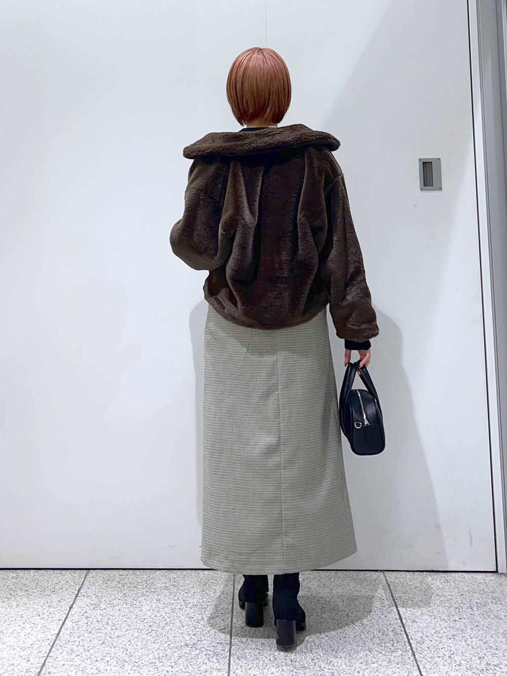 ブラック系のボストンバッグ、ブラック系のブーツ、ブラック系のニット/セーターを着用したレディースの冬コーディネートの3枚目の写真