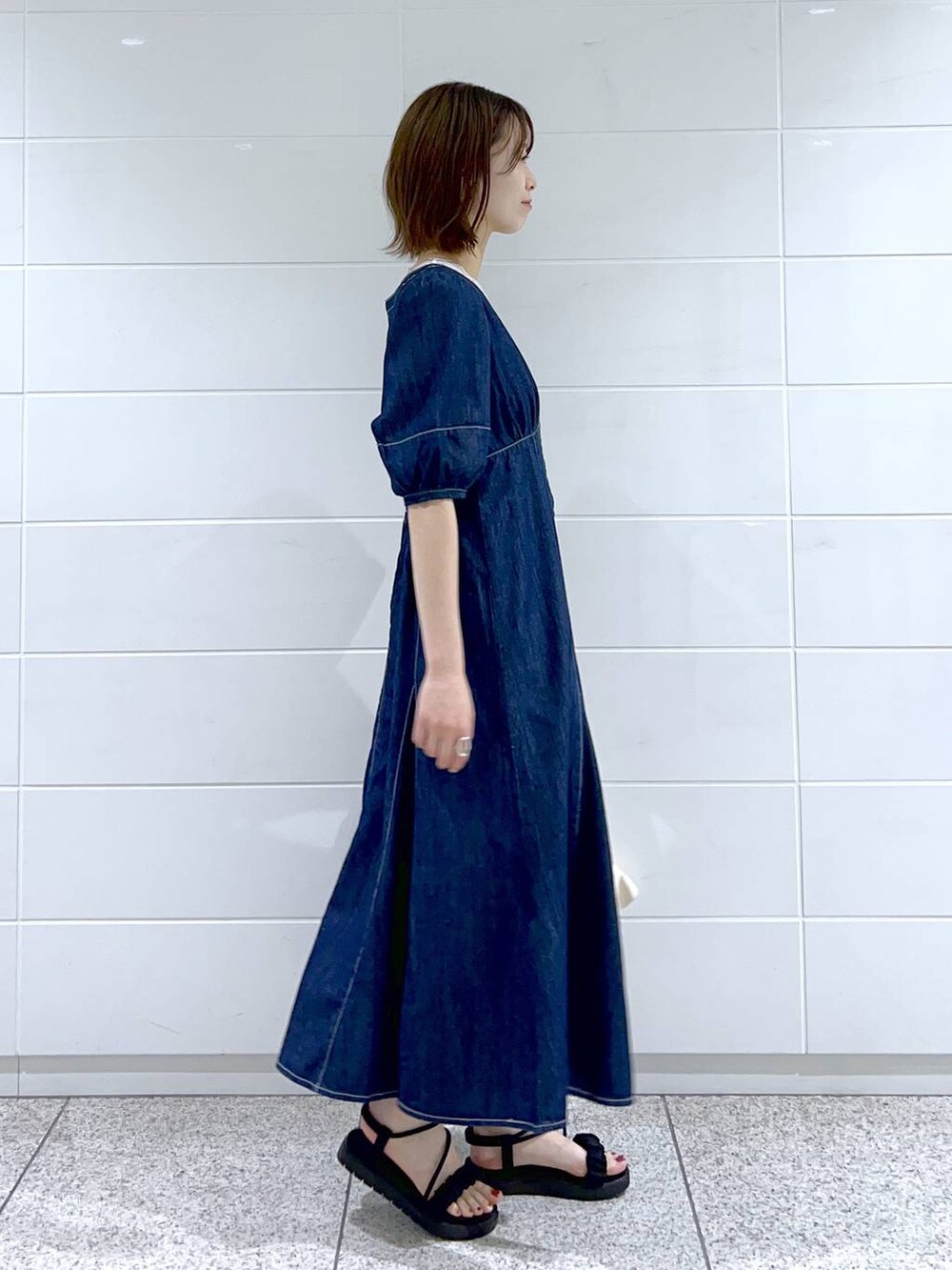 ホワイト系のショルダーバッグ、ホワイト系のタンクトップ、ブルー系のワンピースを着用したレディースの春コーディネートの2枚目の写真