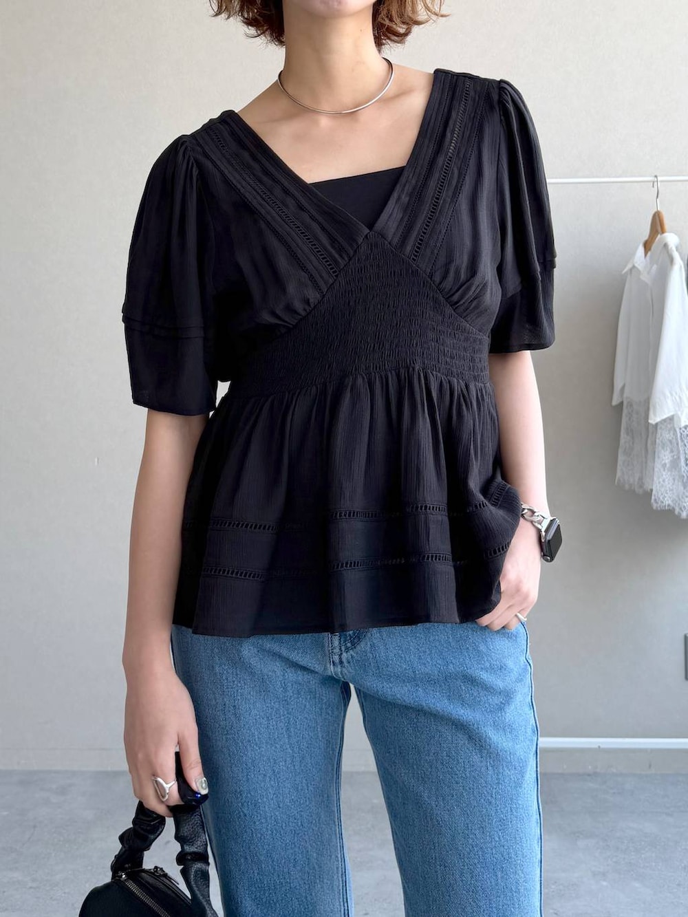 ブルー系のデニムパンツ、ブラック系のキャミソール、ブラック系のショルダーバッグを着用したレディースの春コーディネートの4枚目の写真