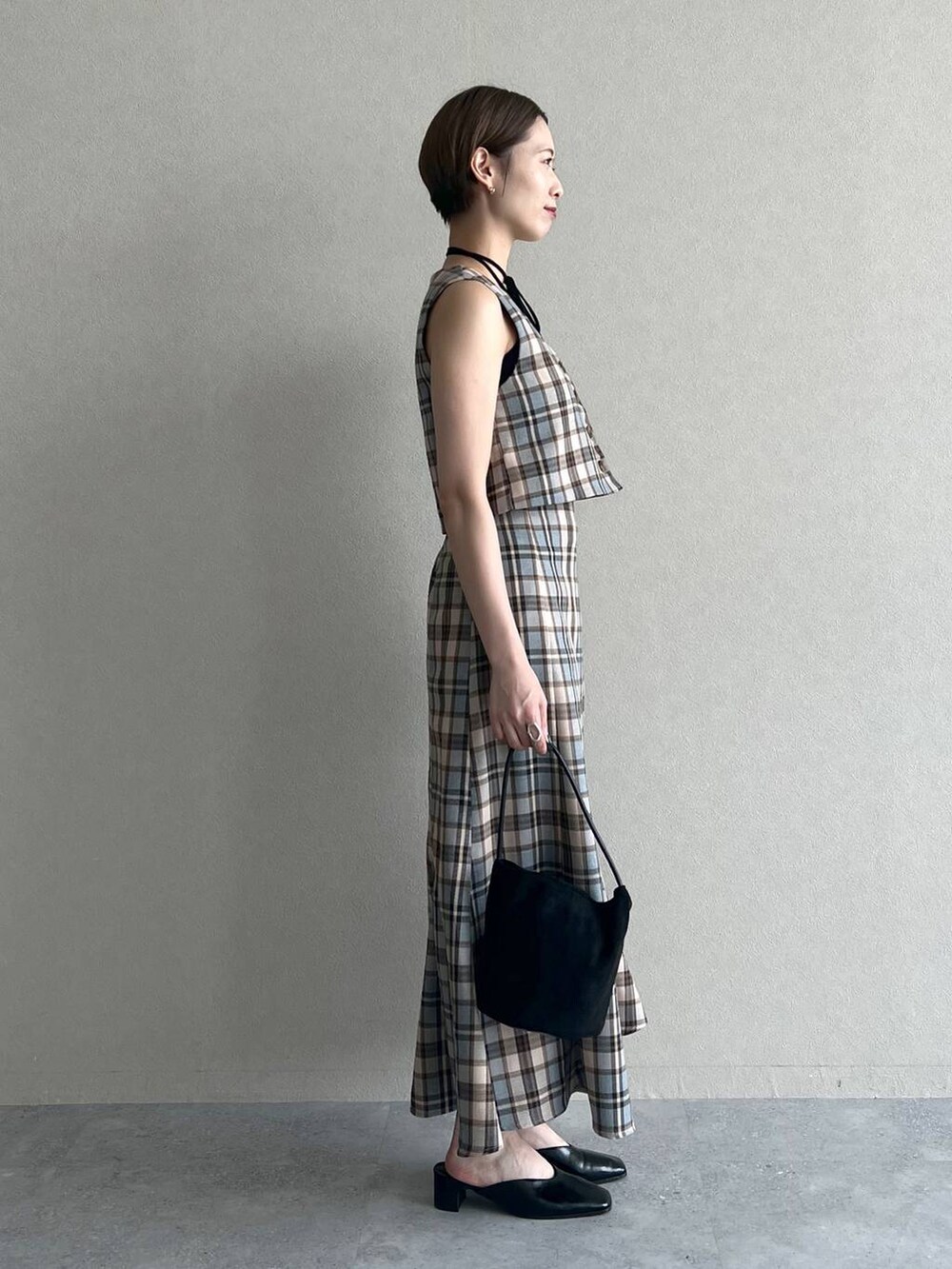 ブラック系のスリッポン、ブラック系のキャミソール、ブラック系のハンドバッグを着用したレディースの秋コーディネートの3枚目の写真