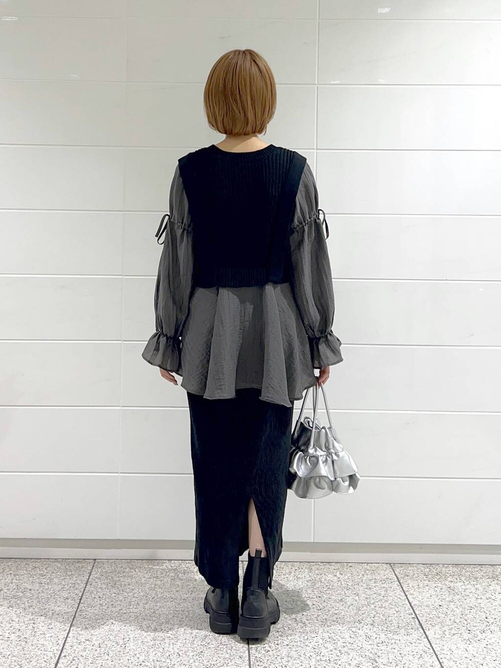 シルバー系のショルダーバッグ、ブラック系のブーツ、ブラック系のスカートを着用したレディースの秋コーディネートの7枚目の写真