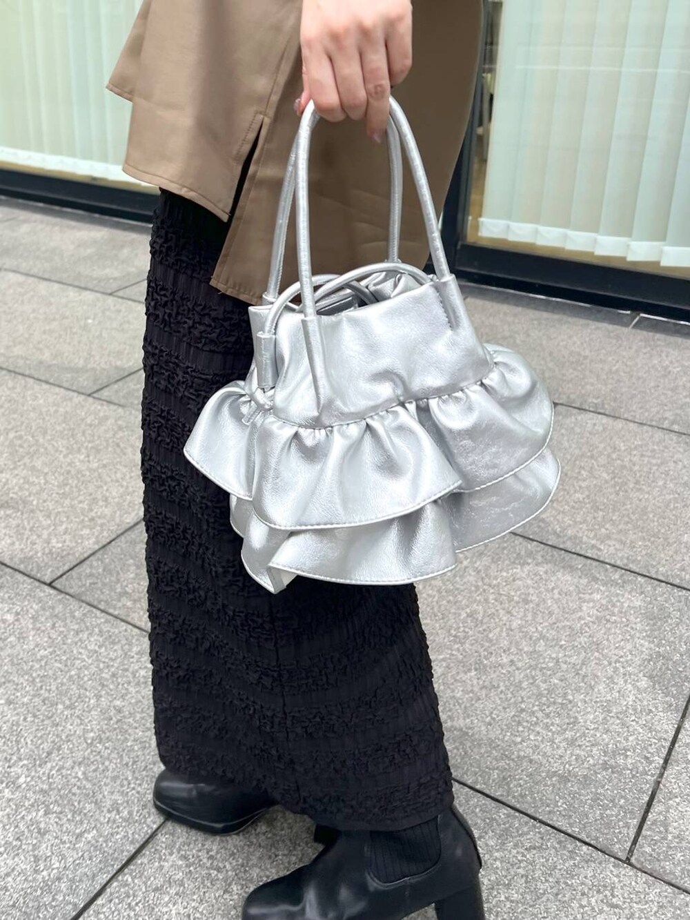 シルバー系のショルダーバッグ、ブラック系のブーツ、ブラック系のスカートを着用したレディースの秋コーディネートの4枚目の写真