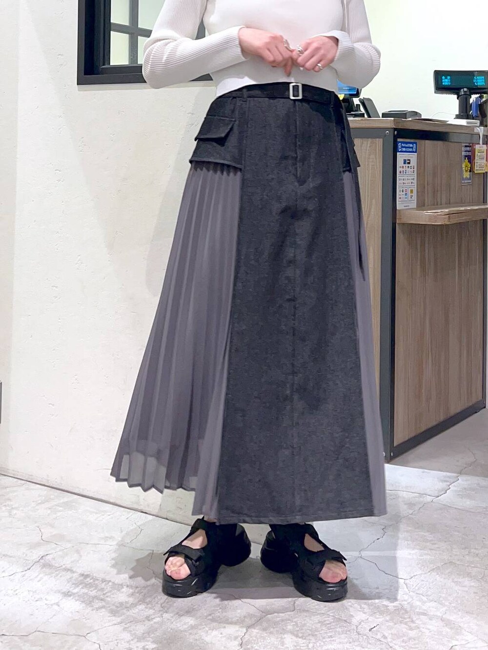 ブラック系のスカート、ホワイト系のカーディガン/ボレロ、ブラック系のサンダルを着用したレディースの春コーディネートの7枚目の写真