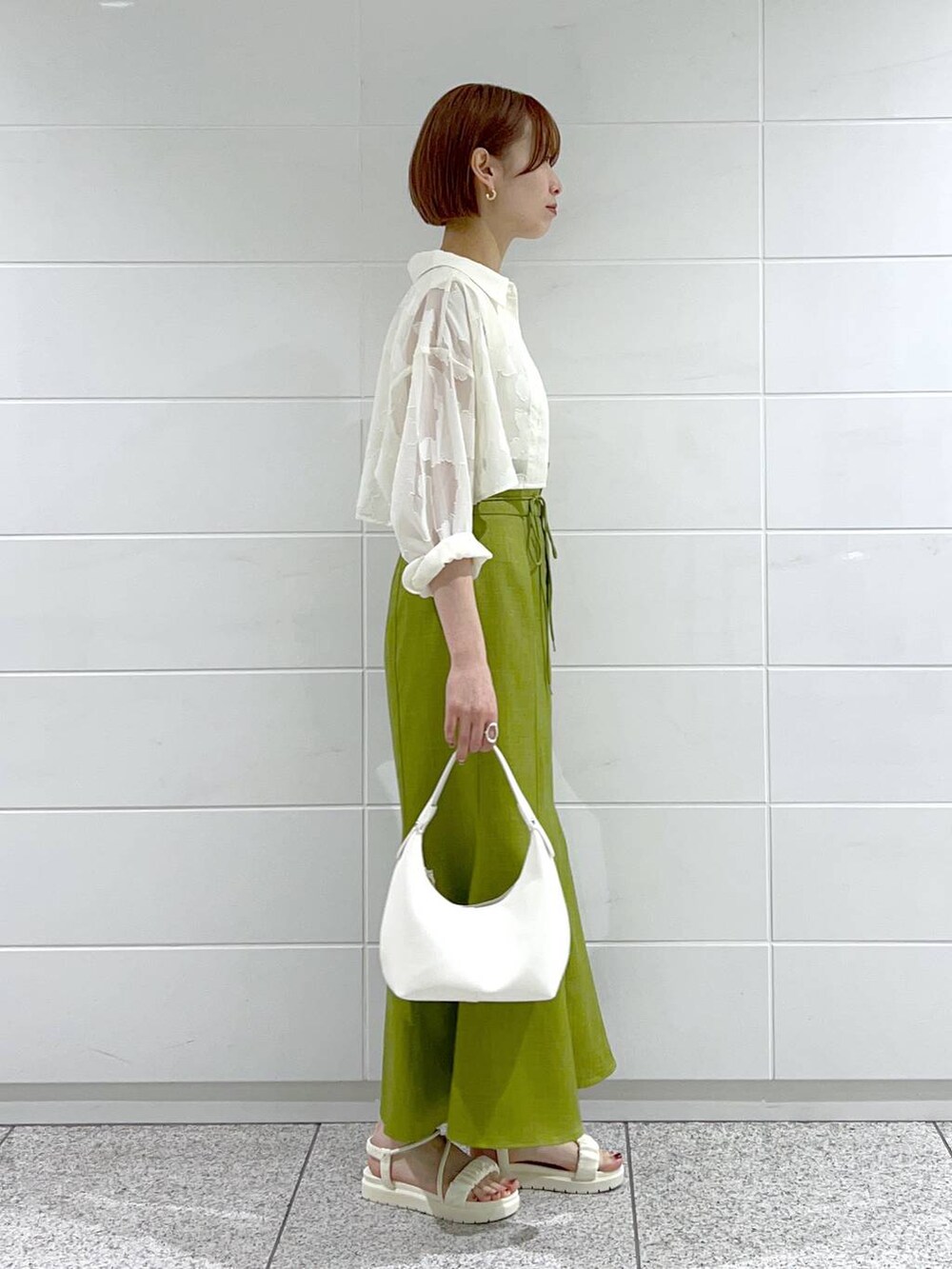 ホワイト系のタンクトップ、グリーン系のスカート、ホワイト系のワンピースを着用したレディースの春コーディネートの2枚目の写真