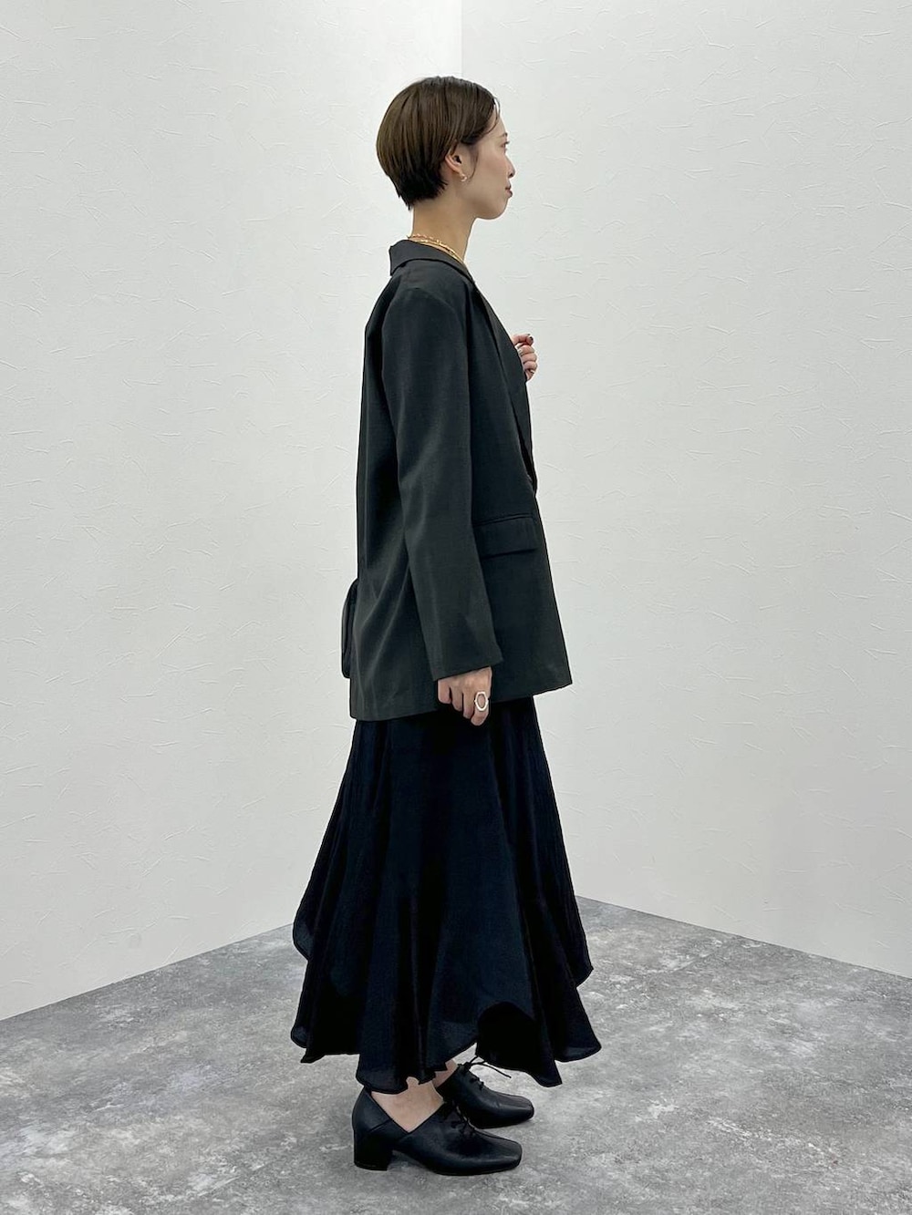 グレー系のテーラードジャケット、ブラック系のハンドバッグ、ブラック系のスカートを着用したレディースの秋コーディネートの2枚目の写真