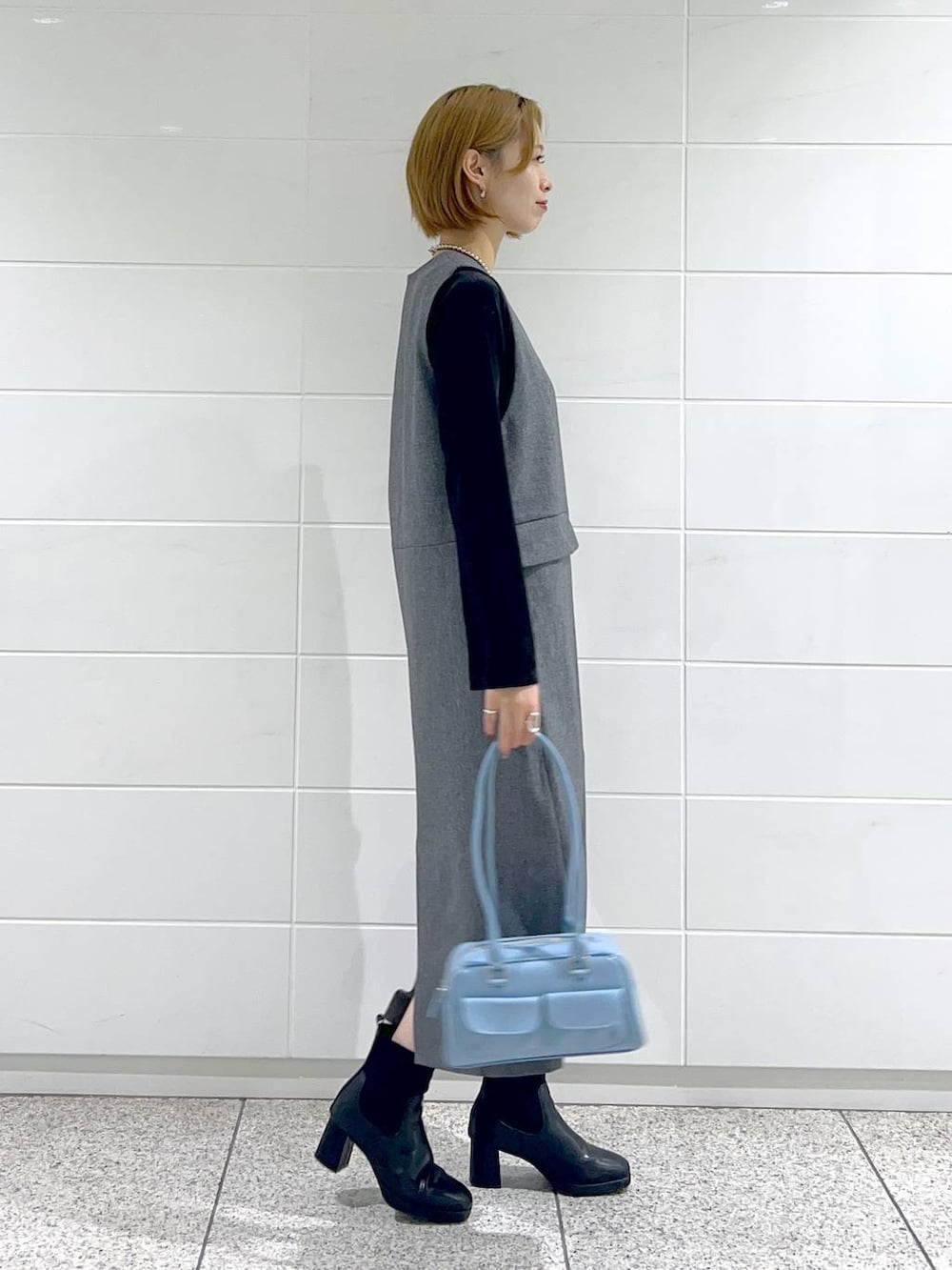 ブラック系のブルゾン、ブラック系のブーツ、グレー系のジャンパースカートを着用したレディースの秋コーディネートの5枚目の写真