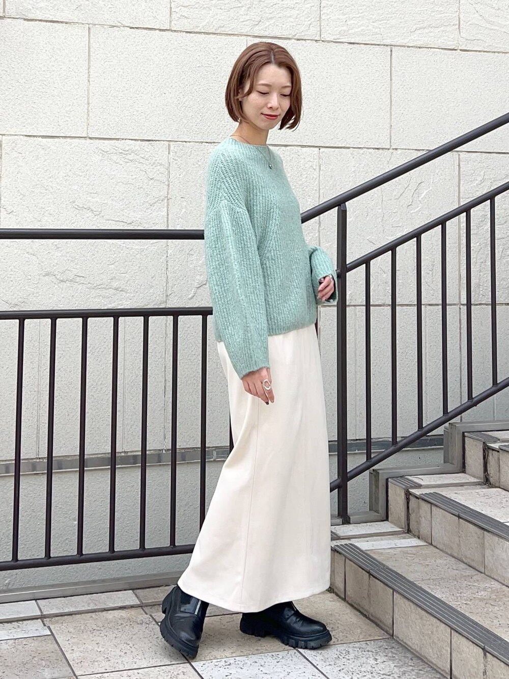 グレー系のノーカラーコート、ブラック系のショルダーバッグ、ブラック系のブーツを着用したレディースの秋コーディネートの6枚目の写真