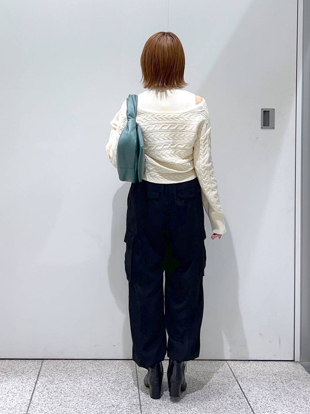 ブラック系のブーツ、グリーン系のハンドバッグ、ホワイト系のニット/セーターを着用したレディースの秋コーディネートの3枚目の写真