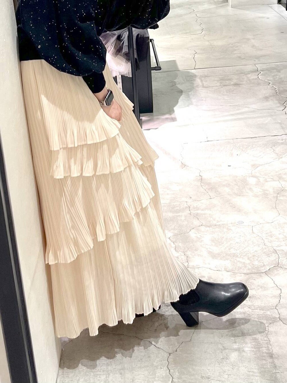 ブラック系のブーツ、ホワイト系のスカート、ブラック系のカーディガン/ボレロを着用したレディースの秋コーディネートの3枚目の写真