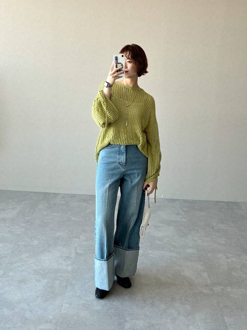 ブラック系のローファー、グリーン系のニット/セーター、ブルー系のデニムパンツを着用したレディースの冬コーディネートの5枚目の写真