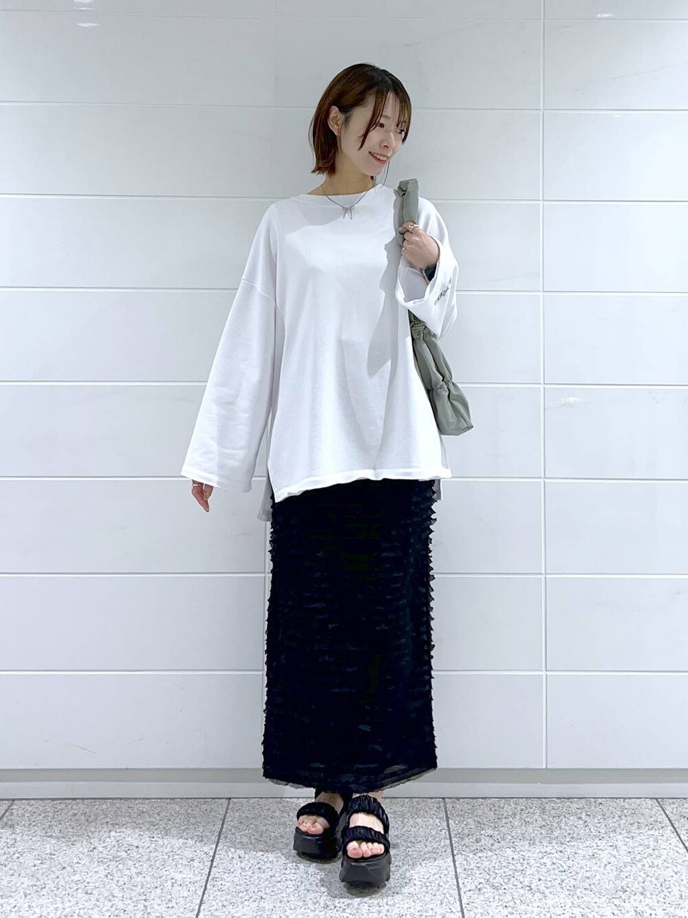 グリーン系のショルダーバッグ、ホワイト系のスウェット、ブラック系のサンダルを着用したレディースの春コーディネートの2枚目の写真