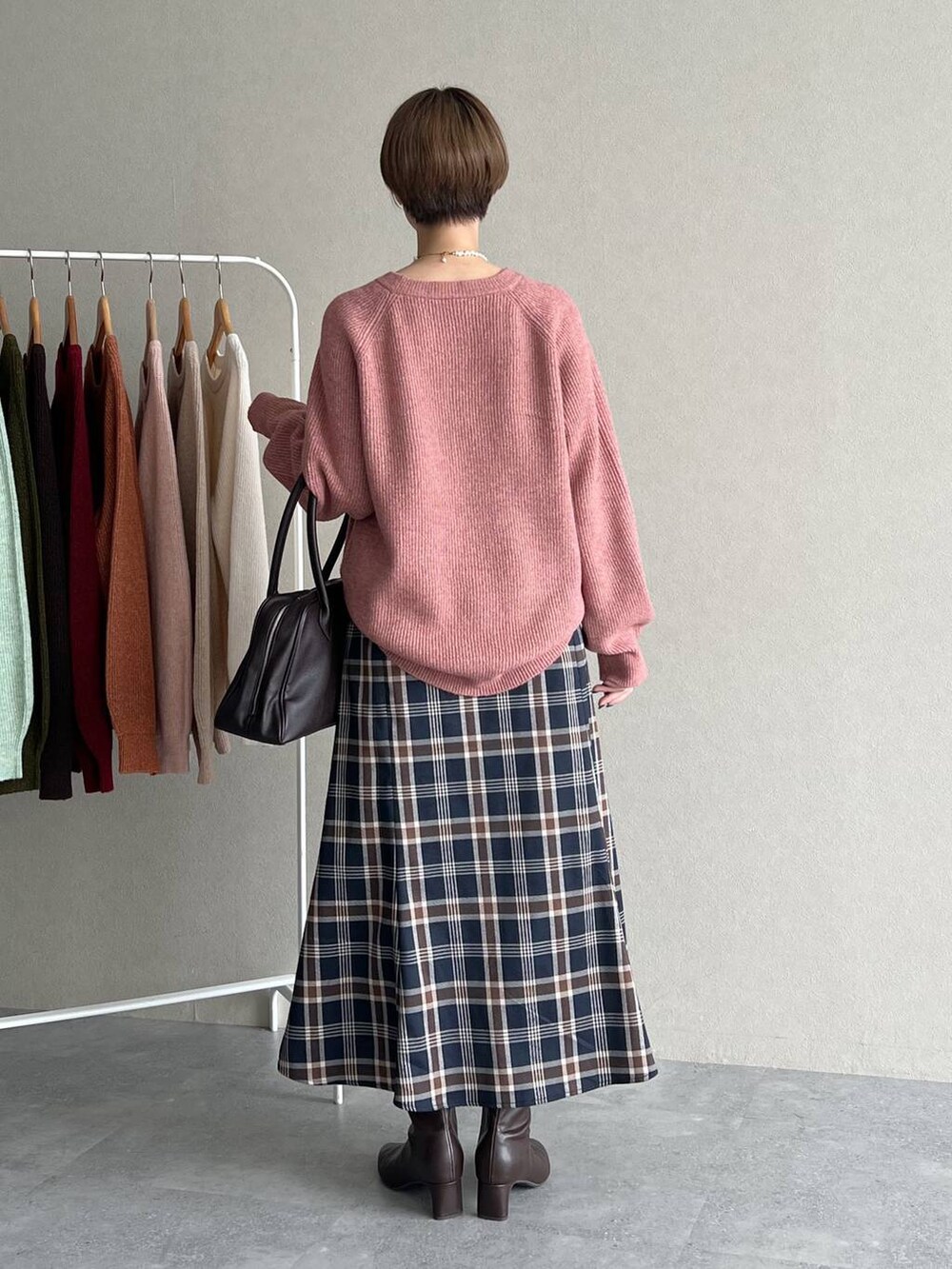 ピンク系のニット/セーター、ブラウン系のブーツ、ブラウン系のトートバッグを着用したレディースの秋コーディネートの3枚目の写真