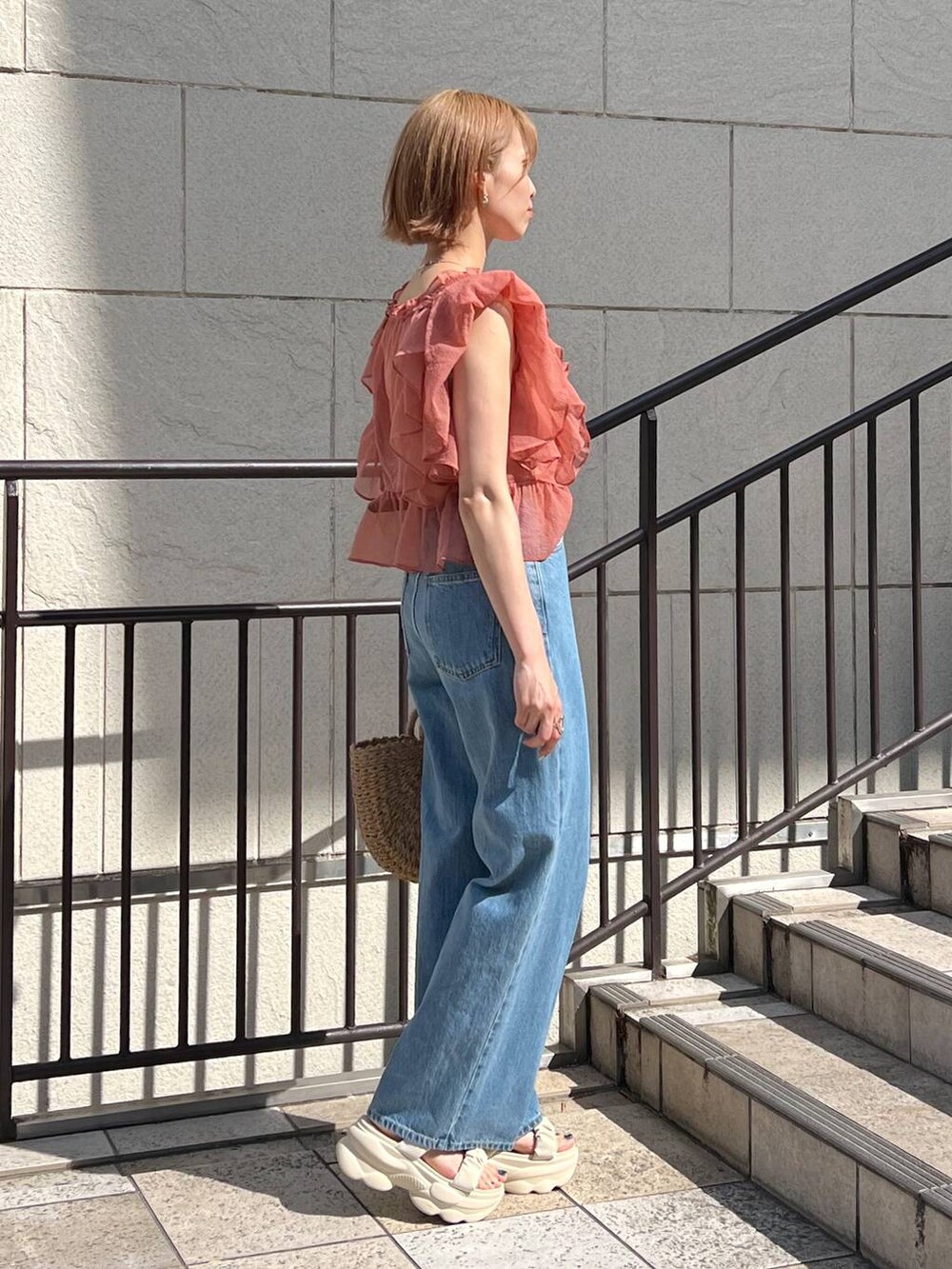 ブルー系のデニムパンツ、ホワイト系のサンダル、ピンク系のシャツ/ブラウスを着用したレディースの春コーディネートの2枚目の写真